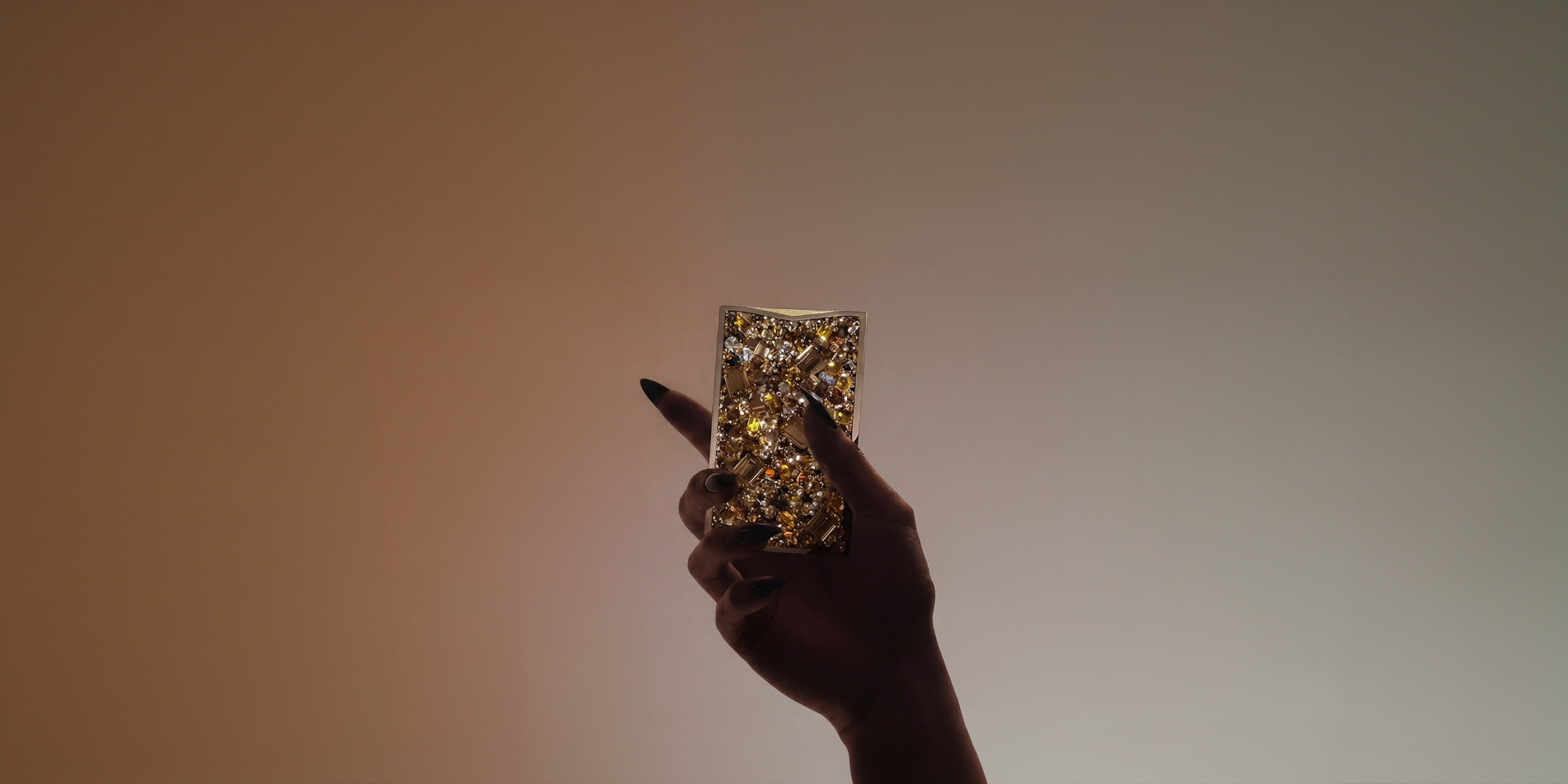 Hand with dark manicured nails holding the NETIC Couture slim wallet in a jewellery-inspired editorial setting