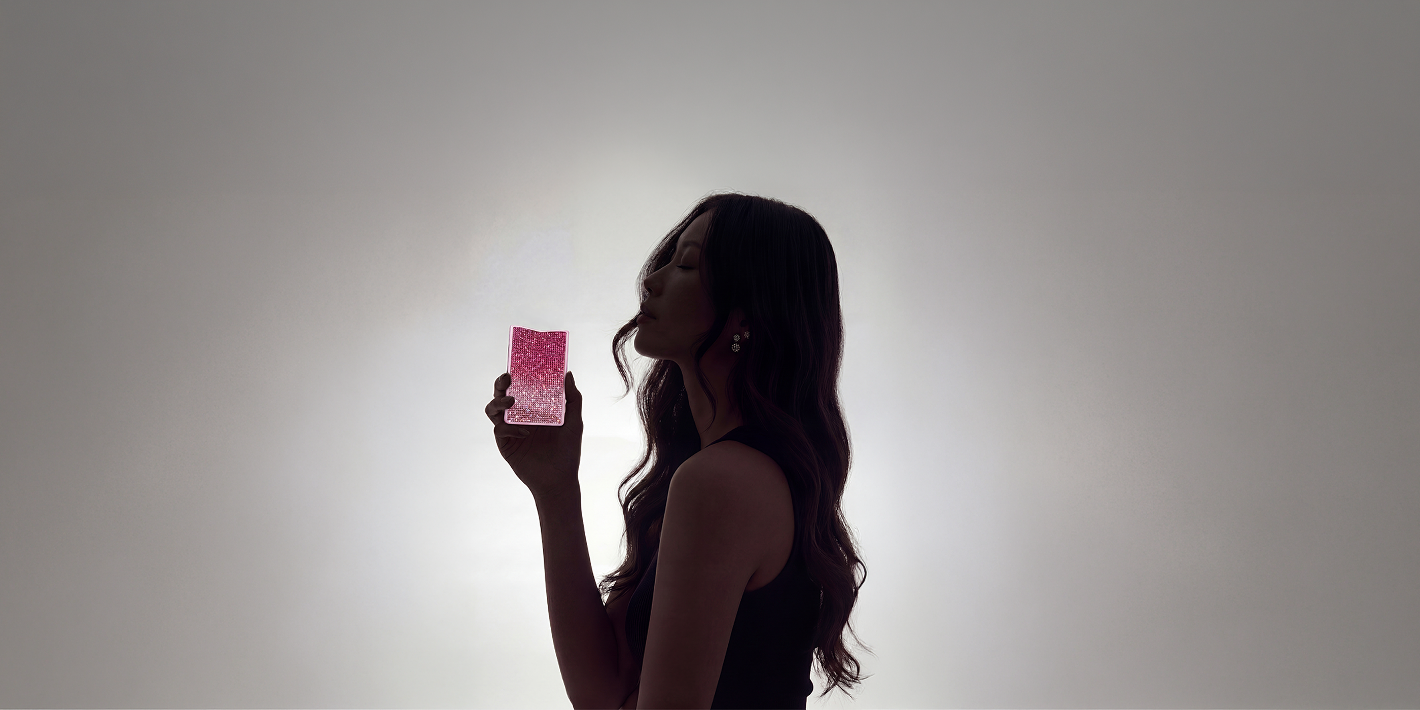 Woman holding the pink NETIC Crystal slim wallet in an editorial setting for slim wallet for women content
